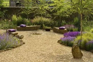 Jardín de grava con asientos de roca y flores silvestres.