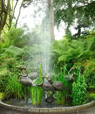 estanque con flamencos de metal y chorro de agua