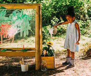 jeune fille jouant à un chevalet de peinture dans une cour