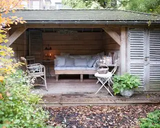 En pavillon i træ med åben side med bænke indeni, der fungerer som en idé til privatliv i haven.