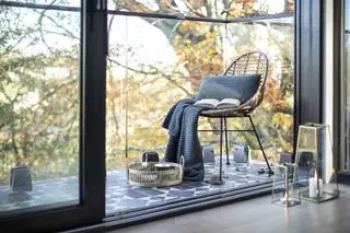 Malý balkon s dlažbou a rákosovou židlí