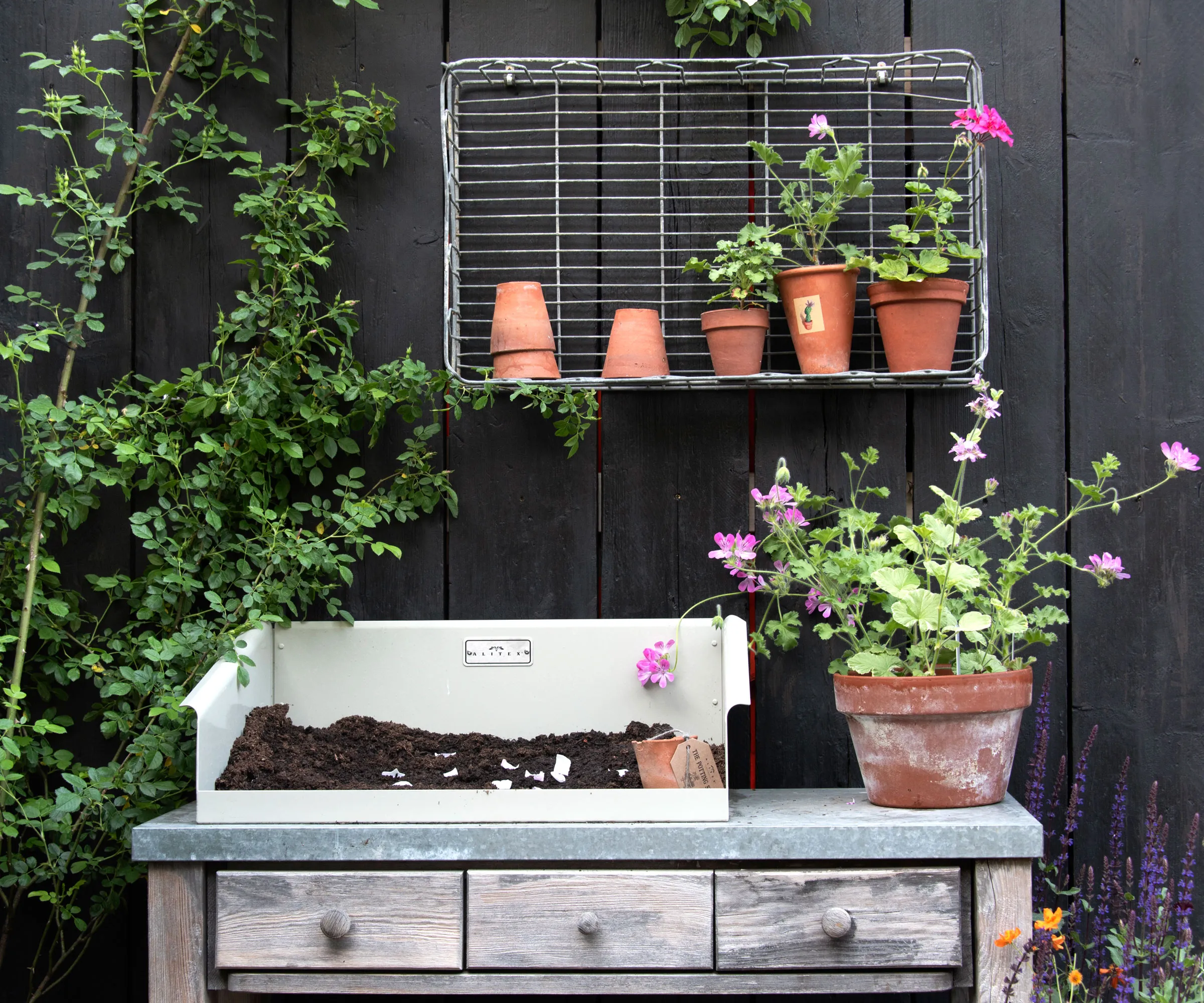 Vintage-Blumentopftisch mit Erde und Pflanzen in Terrakotta-Töpfen' loading='lazy' title=