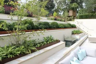 Terraza escalonada con asientos y camas elevadas.