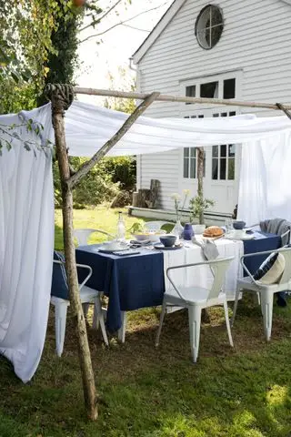 pergola rustica realizzata con rami con vela bianca