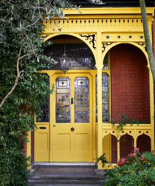 Puerta principal de color amarillo brillante y porche en casa de ladrillo