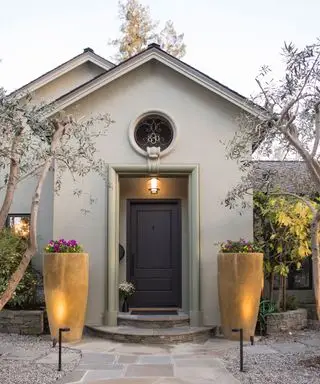 Puerta de entrada con puerta marrón e iluminación.