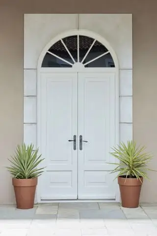 Puerta de entrada doble en blanco con plantas a ambos lados.