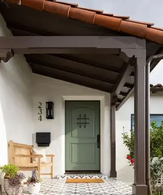 Porche delantero con azulejos llamativos y puerta de entrada verde