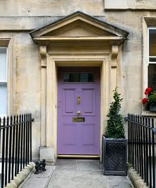 Puerta de entrada violeta en una propiedad de época de piedra clara