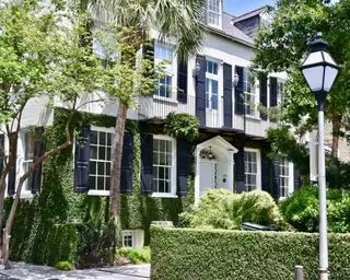 Exterior de una casa de estilo colonial en blanco y negro con contraventanas y balcón