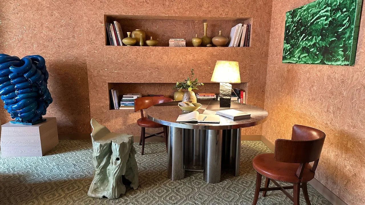 Sala de estar de estilo de mediados de siglo con una mesa cromada, escultura de cobalto y paredes cubiertas de corcho' loading='lazy' title=