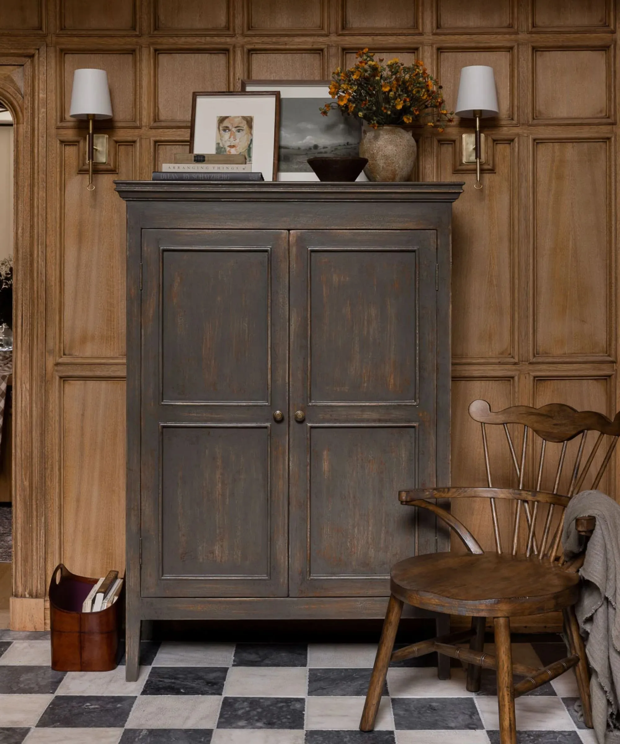 un aparador en la entrada con obras de arte y decoración en la parte superior, dos apliques de pared a cada lado y una silla de madera de inspiración vintage' loading='lazy' title=