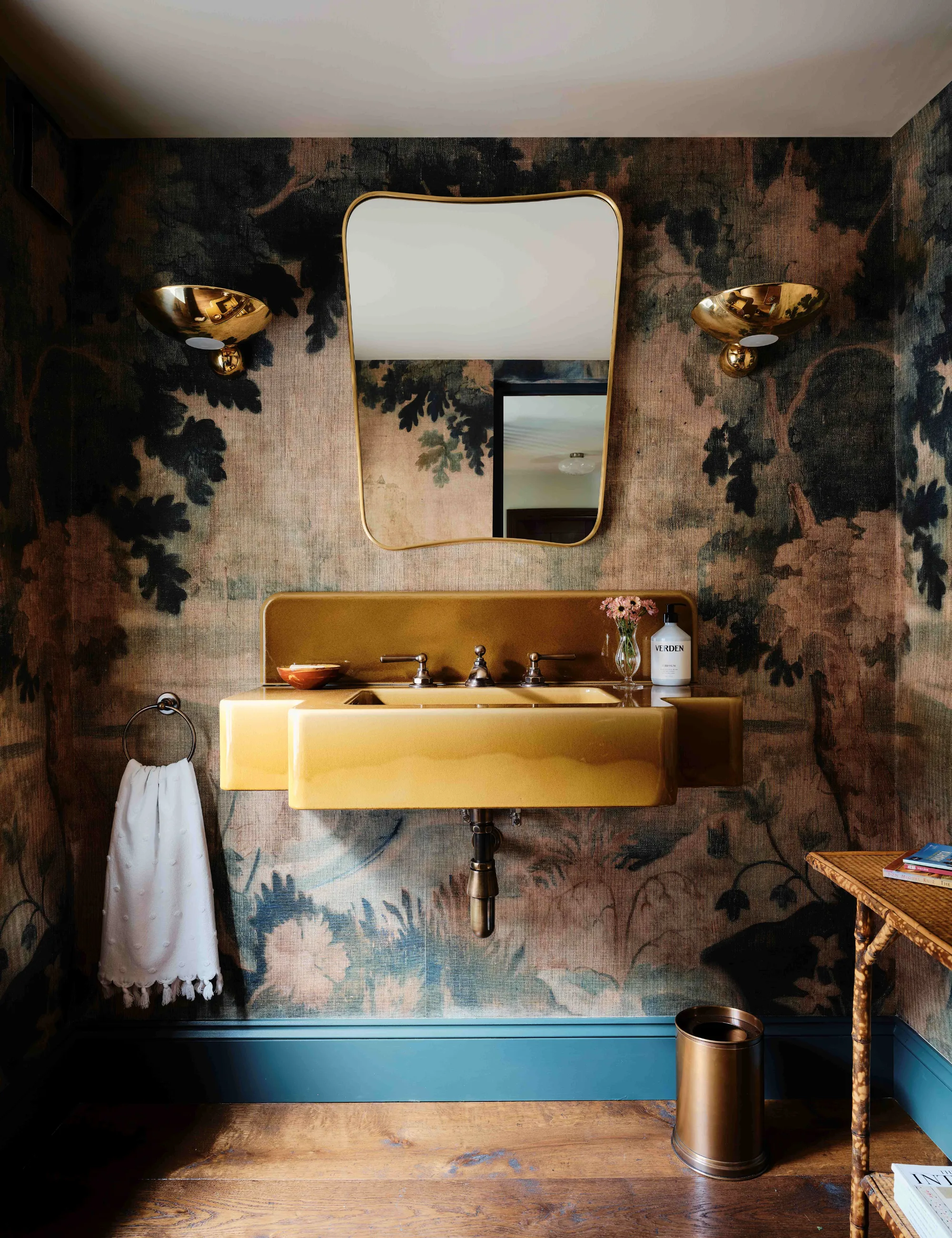 Gæstebadeværelse med vægmaleri tapet, gult håndvask og skinnende messing badeværelsesudstyr' loading='lazy' title=
