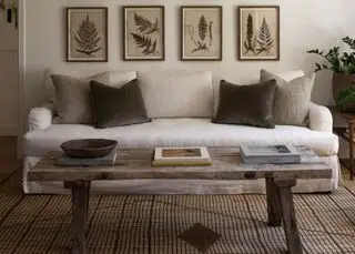Gårdsinnredningsideer, kremsofa på brunstripet teppe, fire kunstverk, presset blomsterstil, salongbord i tre