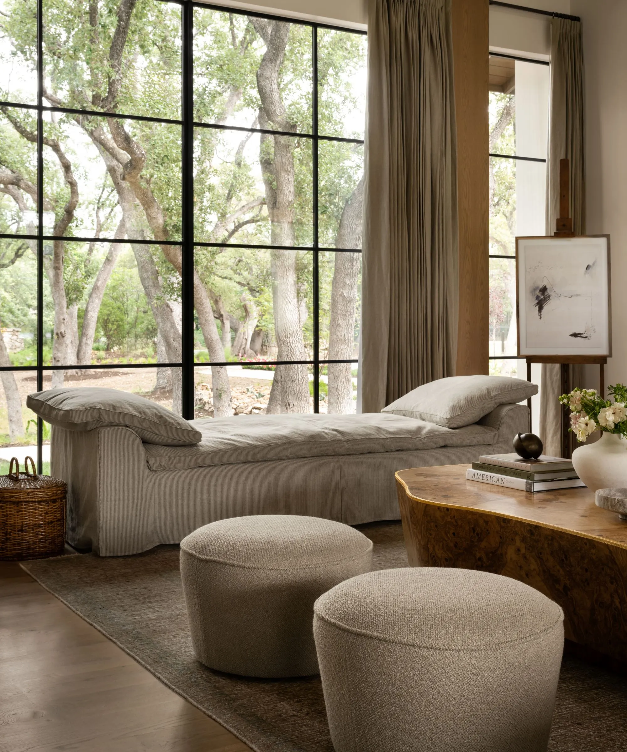 sala de estar com sofá e poltrona estampados e tapete texturizado de ervas marinhas e mesa de centro de madeira pintada em cores e arte nas paredes atrás com espelhos simétricos' loading='lazy' title=