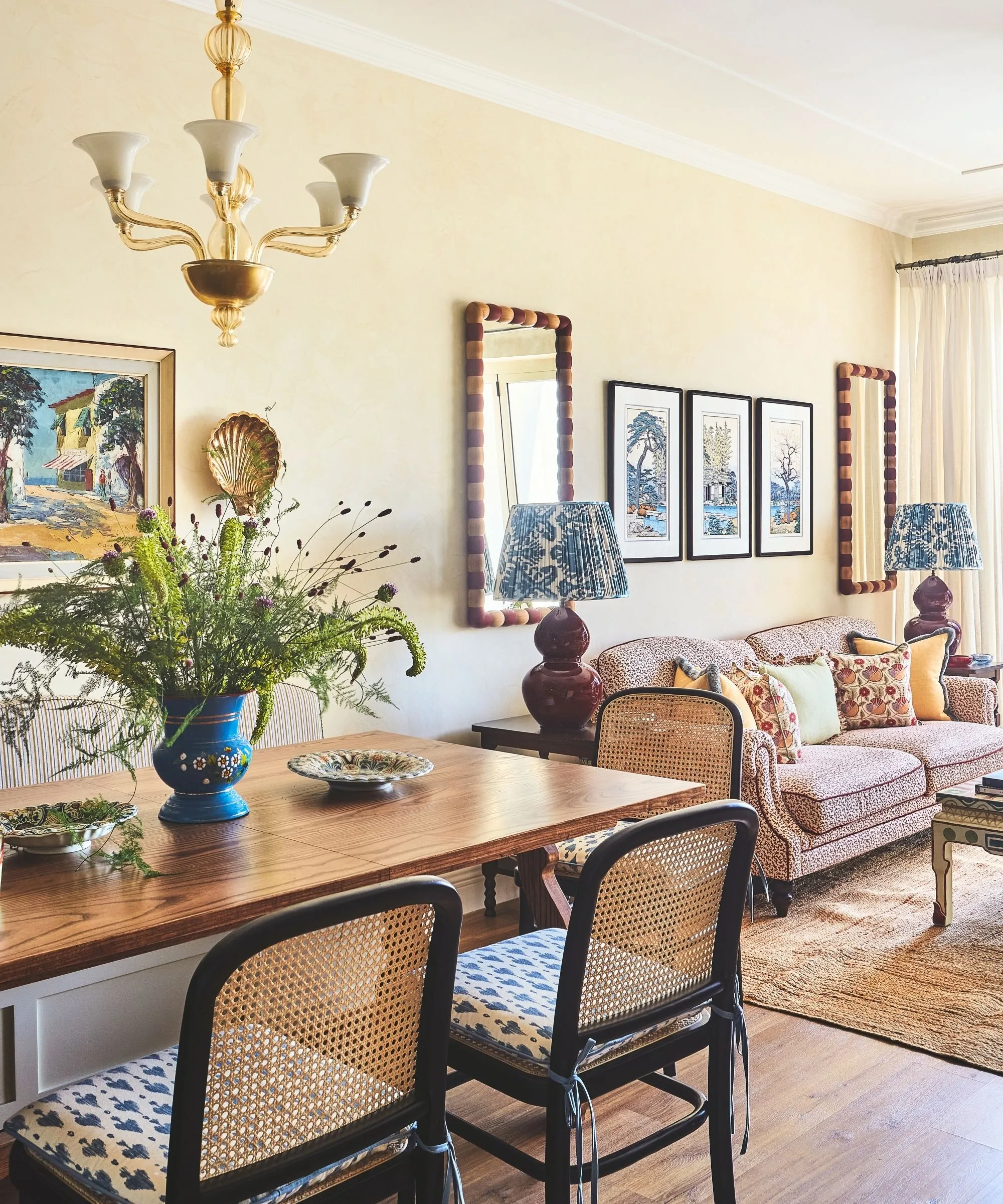 grande sala de estar pintada de ocre com uma antiga lareira de mármore vermelho uma grande janela sofá amarelo curvo mesa de centro redonda branca e poltronas curvas roxas' loading='lazy' title=