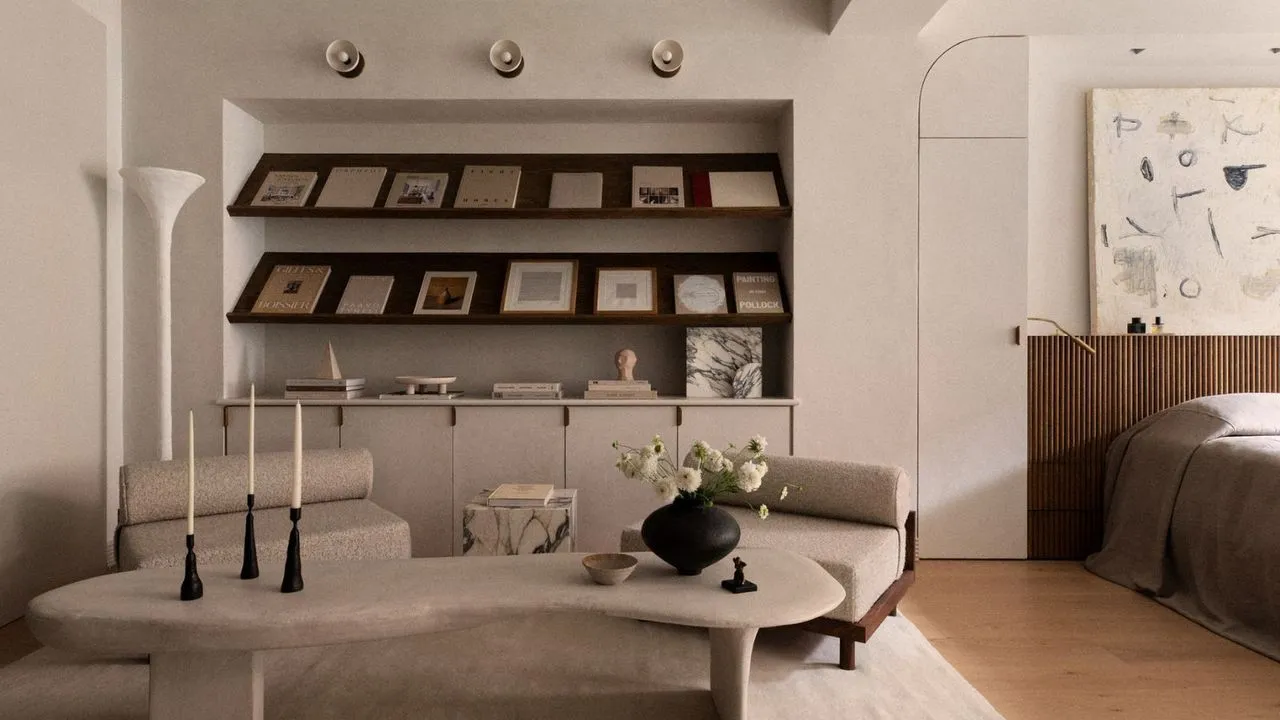 סלון מינימליסטי עם כיסאות בוקל שולחן קפה מאבן ומדפי ספרים' loading='lazy' title=