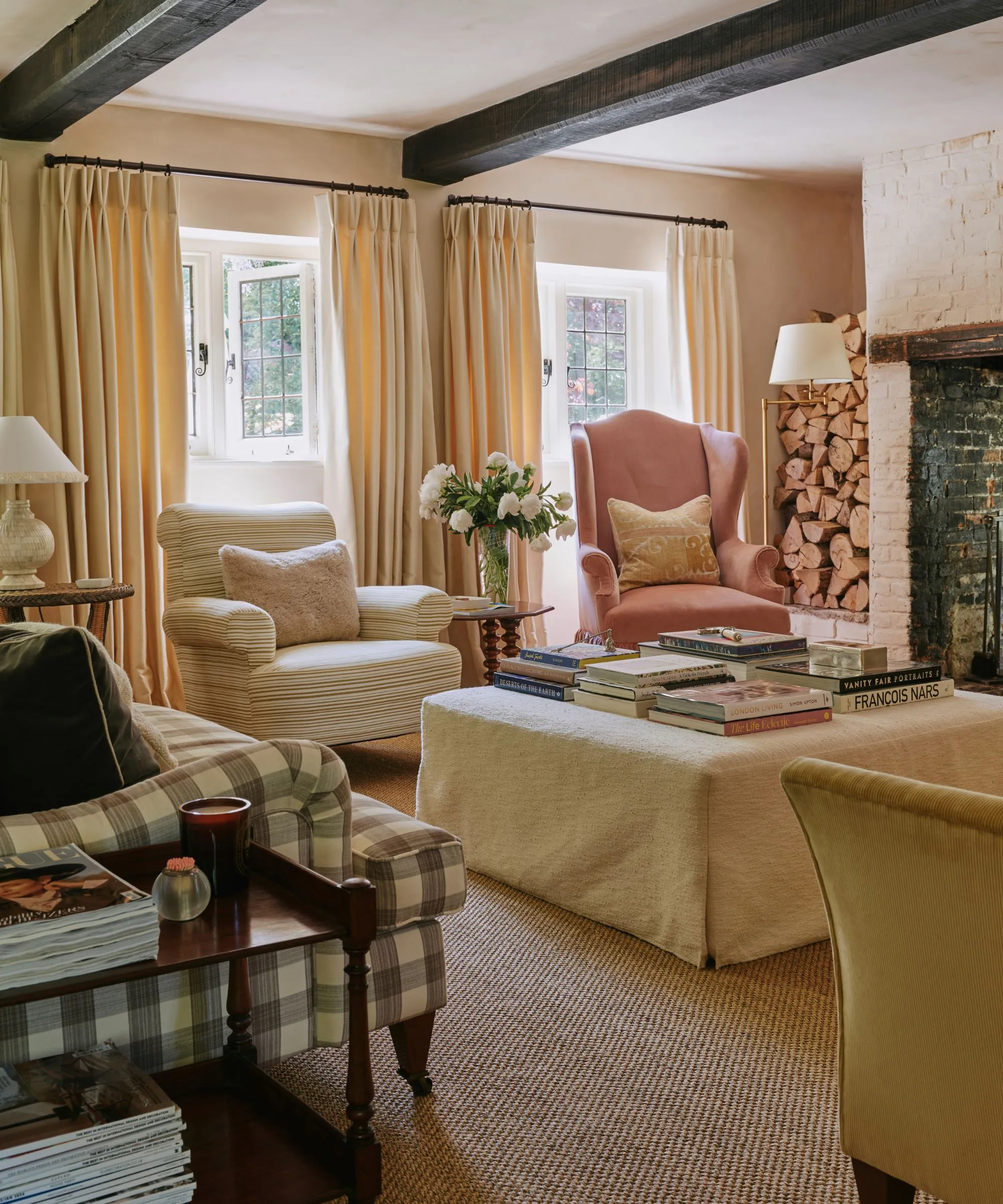 קוטג' כפרי סלון עם קורות עץ כהות, ספת ג'ינג'ם שתי כורסאות לא תואמות וסלון נייטרלי מכוסה עות'מאנית' loading='lazy' title=