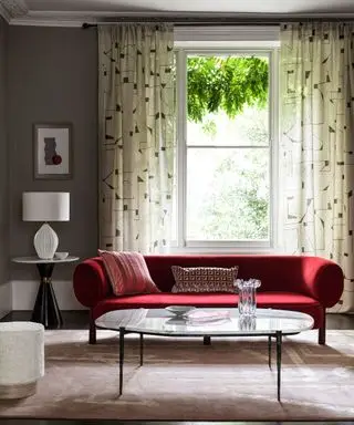 monochromatický obývací pokoj se zářivou červenou sametovou pohovkou a geometrickým designem záclony