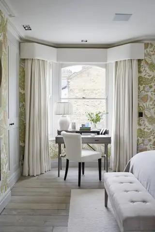 Cortinas color crema, mesa de oficina gris, silla blanca con patas negras