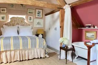 Vanrenen GW Designs dormitorio abuhardillado con vigas y baño oculto