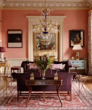 Rotes Wohnzimmer mit Antiquitäten, Kronleuchter und Esstisch aus Holz