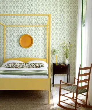 Chambre lumineuse avec papier peint vert botanique, lit à baldaquin jaune vif et accessoires, chaise à bascule en bois