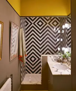 salle de douche jaune et taupe avec carrelage géométrique noir et blanc