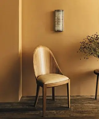 Mur jaune avec chaise en bois au premier plan