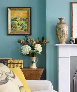 Lyseblå stue, sofa, kande - vase med blomster, antik vase og maleri