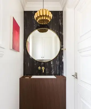 Une salle de bains de style art déco avec un miroir circulaire et un luminaire tendance
