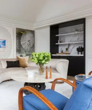 Un salon d'inspiration art déco avec un canapé blanc sculptural et un fauteuil bleu, ainsi qu'un marbre en arrière-plan