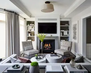 Gemütliches Wohnzimmer mit Sitzgelegenheiten rund um den Kamin und TV