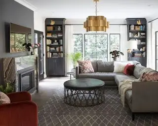 Großes Wohnzimmer mit grau gestrichener Wand, Sofa, Teppich und Nischenregalen