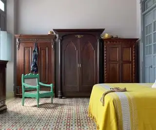 Armarios oscuros con cama cubierta de color amarillo en primer plano