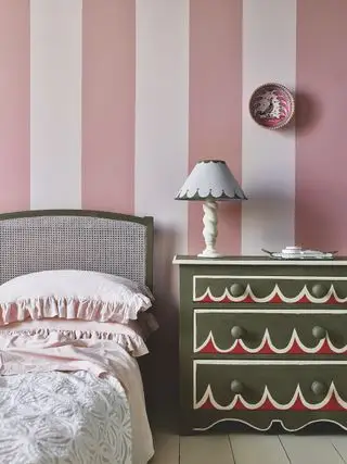 paredes a rayas rosas y blancas en un dormitorio con cómoda pintada