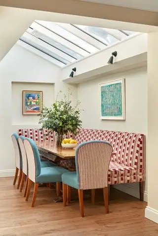 Mesa de comedor con banqueta y sillas de comedor bajo tragaluces.