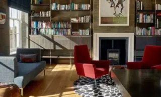 Salón con sofá y sillones, suelo de madera y alfombra.