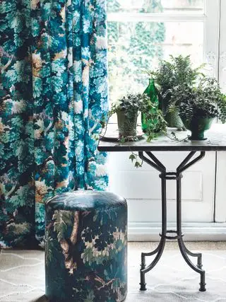 Mesa de jardín vintage junto a una ventana con un grupo de plantas en macetas