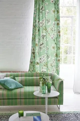 salón blanco y verde con cortinas florales verdes, sofá a cuadros verdes, mesa auxiliar y alfombra negra y verde