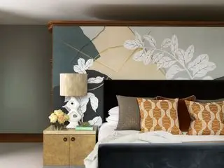 Dormitorio con cabecero mural y mesa auxiliar.