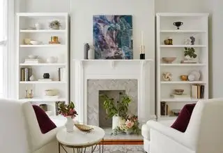 Pequeño salón blanco con sillones blancos.