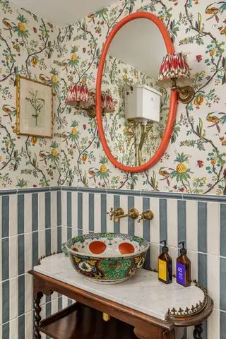 Medio baño con tocador y pared empapelada y rayada