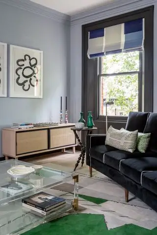 Salón con sofá, mesa de centro, aparador, alfombra y persiana romana.