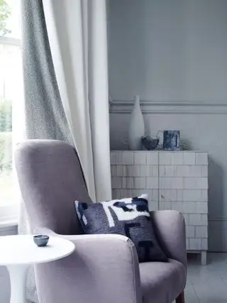 lenestol og sidebord ved siden av vindu med gardin med mønstret fôr