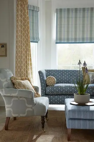stue med gule gardiner og blå persienner ved siden av blå sofa og grå lenestol