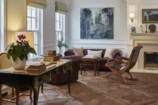 Suelos de parquet en salón tradicional con sofá de cuero, sillón y escritorio.