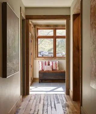 Pasillo de granja con cojines en un banco, suelos de madera, marcos de puertas, ventanas
