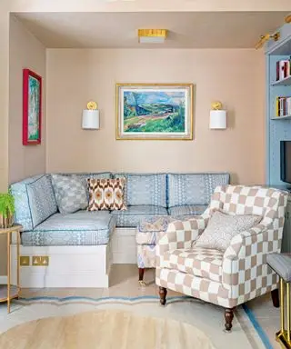 Pequeño salón con sofá estampado azul, sillón a cuadros, obras de arte y apliques en las paredes, alfombra colorida