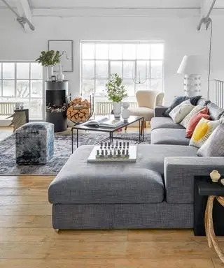 Åben stue med hvide vægge og l-formet sofa